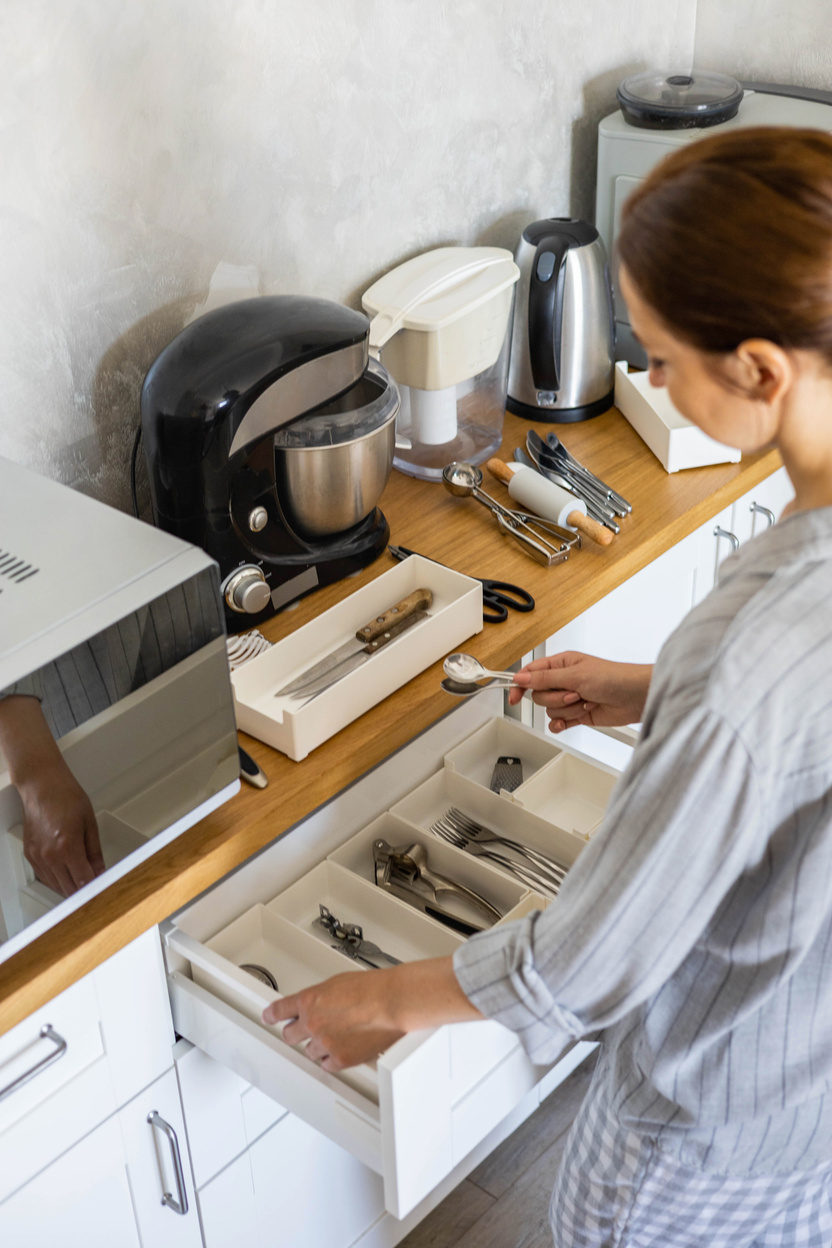 modern housewife tidying up kitchen cupboard during general cleaning or tidying up
